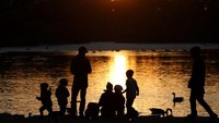 Siluet pejalan kaki melawan matahari terbenam yang dipantulkan di Humboldt Lagoon di Humboldt Park saat suhu musim semi yang lebih hangat di Chicago, Amerika Serikat. AP Photo/Shafkat Anowar