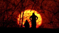 Siluet warga saat menikmati matahari terbenam di Kansas, Amerika Serikat. AP Photo/Charlie Riedel