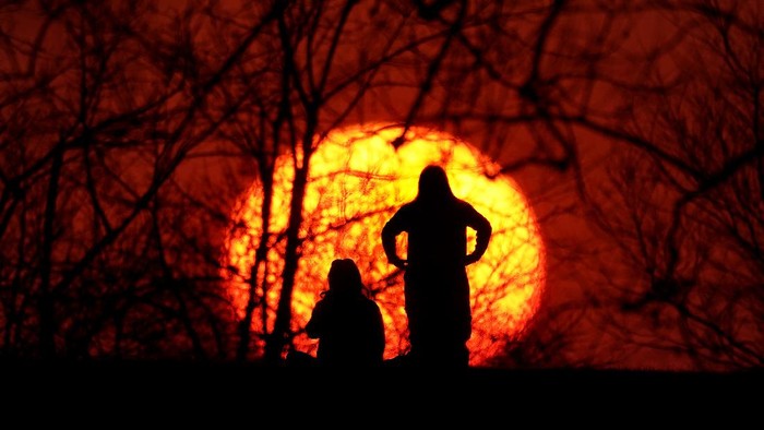 Menikmati Indahnya Matahari Terbenam Girls are silhouetted against the setting sun as they enjoy a spring-like day Saturday, March 6, 2021, in Kansas City, Mo.
