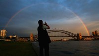 Pelangi muncul di atas Sydney Harbour Bridge di Sydney, Australia. Getty Images/Cameron Spencer