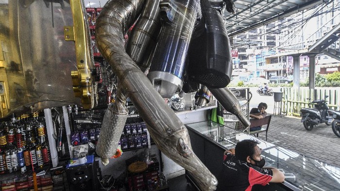 Penjual knalpot dan aksesori modifikasi sepeda motor melayani calon pembeli di kawasan Kampung Melayu, Jakarta, Jumat (19/3/2021). Maraknya razia knalpot racing atau bising oleh pihak kepolisian berdampak pada turunnya penjualan knalpot aftermarket (suku cadang pengganti yang dibuat oleh perusahaan selain produsen asli kendaraan) yang memiliki suara bising. ANTARA FOTO/Muhammad Adimaja/foc.