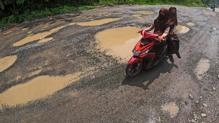 Pengendara melintasi Jalan Lintas Sumatera yang rusak di Sungai Lansek, Sijunjung, Sumatera Barat, Kamis (18/3/2021). Jalan penghubung Sumatera Barat dengan Jambi itu rusak dan berlubang di sejumlah titik sehingga membahayakan pengendara. ANTARA FOTO/Wahdi Septiawan/foc.