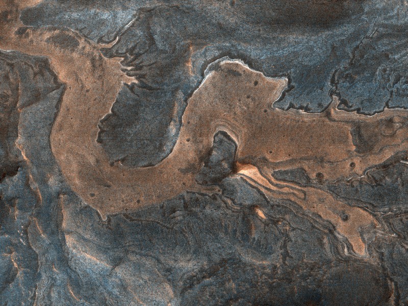 Bagian dari lantai ngarai dan dinding batu di barat daya Melas Chasma di Mars berkelok-kelok dalam pola yang menyerupai naga. Kamera HiRISE di Mars Reconnaissance Orbiter menangkap gambar itu pada 4 Juli 2007.