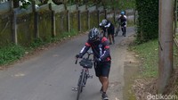 Pesepeda menuntun sepeda saat melewati tanjakan. Menuntun merupakan pilihan sulit saat lelah dan kehabisan tenaga.