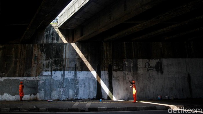 Menyiapkan 'Kanvas' Raksasa Para petugas PPSU Kelurahan Bintaro mengecat dinding kolong tol di Jl Bintaro Permai Raya, Jakarta Selatan, Sabtu (20/3/2021). Cat putih tersebut akan menjadi cat dasar atau semacam kanvas untuk pembuatan lukisan mural. Sebelumnya, dinding kolong tol ini banyak terdapat coretan, grafiti dan poster iklan.