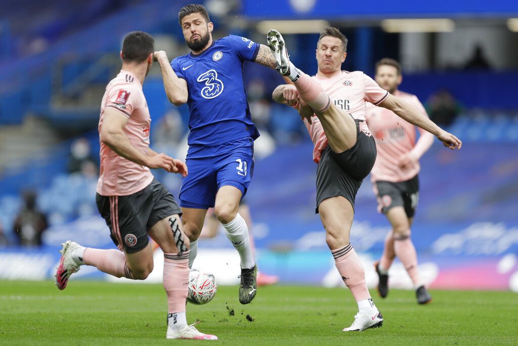 Chelsea's Olivier Giroud, center, is challenged by Sheffield United's Phil Jagielka, right, during the English FA Cup quarterfinal soccer match between Chelsea and Sheffield United at the Stamford Bridge stadium in London, Sunday, March 21, 2021. (AP Photo/Kirsty Wigglesworth)