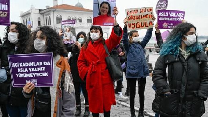 A protester (C) holds a picture of a woman killed by a man, where it is reading 