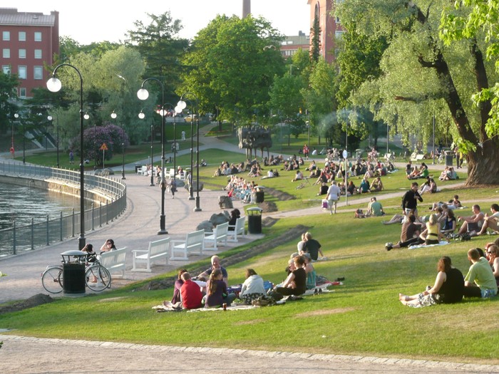 Tampere, Finland – June 5, 2008: People sunbathe and sit on the grass near Tammerkoski, a channel of rapids in Tampere, Finland. Some people walk around the area. (istockphoto/KreangchaiRungfamai)