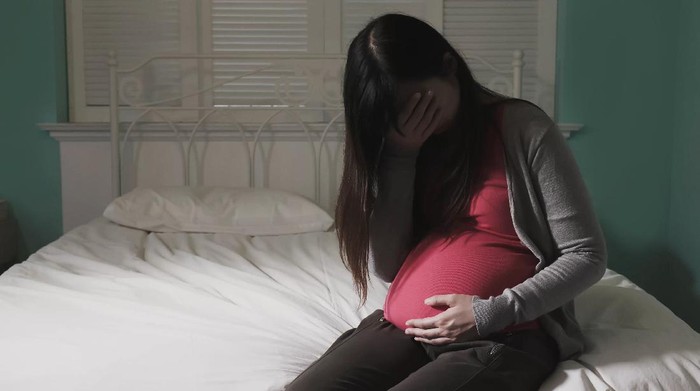 pregnant women sit on the bed and feel depression at home
