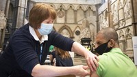 Seorang petugas tengah menyuntikan vaksin COVID-19 kepada warga di Gereja Westminster Abbey, London, Inggris. Stefan Rousseau/PA via AP.