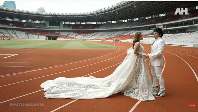 Video itu lalu memperlihatkan keduanya beraksi di depan kamera dengan look dan latar yang berbeda-beda. Untuk look pertama, keduanya kompak dalam balutan busana serba putih. Aurel memakai gaun sleeveless dengan train atau ekor yang sangat panjang. Beratnya 10 kg, kata seseorang yang membantu Aurel berjalan sambil mengangkat gaun tersebut.  (Foto: YouTube/Atta Halilintar)