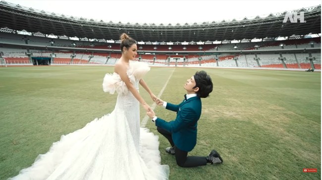 Atta pun mencoba bergaya classy dan elegan dengan setelan dengan jas berwarna midnight blue. Saat pemotretan, Atta berpose seolah-olah sedang melamar Aurel Hermansyah. Mau kah kamu menjadi ibu dari anak-anakku? tanya Atta dengan tatapan mesra di tengah hamparan lapangan hijau GBK yang megah itu. (Foto: YouTube/Atta Halilintar)