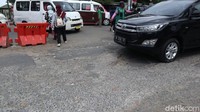 Pak Ogah berdiri di atas Jl Raya Legok yang rusak. Terlihat permukaan jalan ini hancur.(Nisrina Khairunnisa/detikcom)
