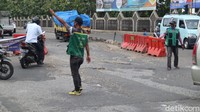 Ini pemandangan di ruas Jl Raya Legok-Karawaci, Kabupaten Tangerang, Provinsi Banten. Pak Ogah atau pengatur jalan tidak resmi beraksi di atas jalan rusak ini. (Nisrina Khairunnisa/detikcom)