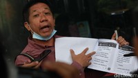 Effendi Gazali menunjukkan sejumlah dokumen kepada jurnalis saat tiba di Gedung KPK.