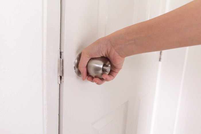 close up women twists doorknob to enter the bathroom