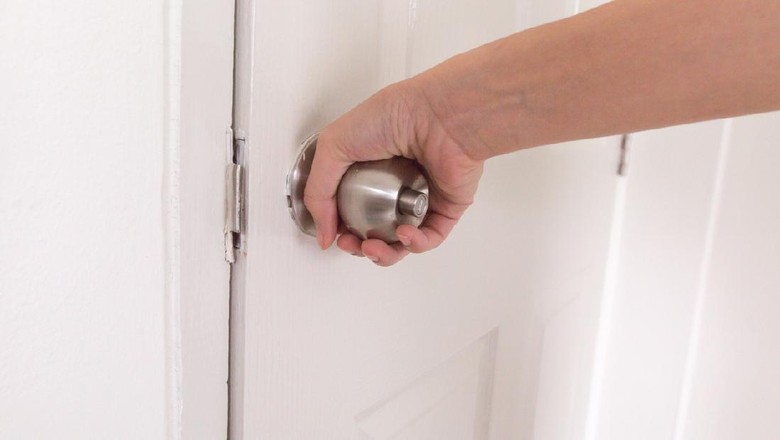 close up women twists doorknob to enter the bathroom