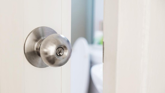 close up women twists doorknob to enter the bathroom