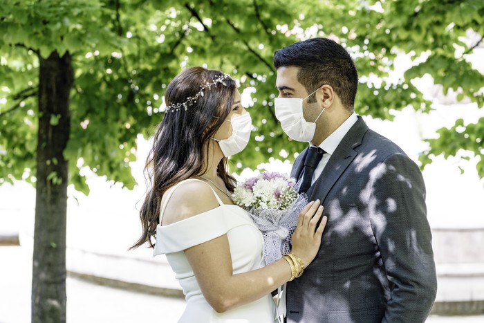 1227435116 bride and groom in a face protection mask