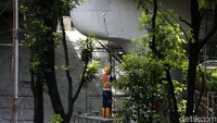 Petugas tampak memakai scaffolding dan bambu untuk mengecat bagian atas dinding.