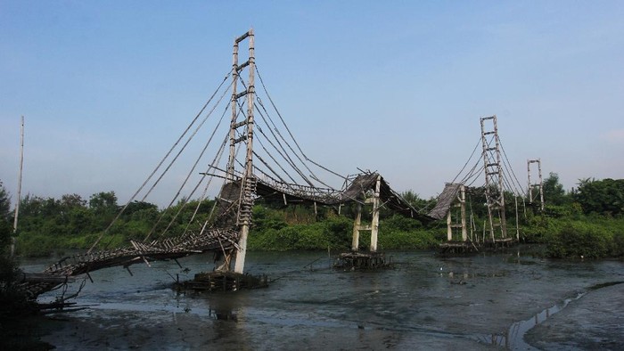 Warga melintas di dekat jembatan bambu di kawasan Ekowisata Mangrove Wonorejo, Surabaya, Jawa Timur, Sabtu (27/3/2021). Jembatan bambu yang dibangun pada tahun 2018 dengan panjang sekitar 600 meter dan tinggi sekitar 12 meter itu kondisinya rusak dan sudah tidak bisa dipergunakan lagi. ANTARA FOTO/Didik Suhartono/hp.