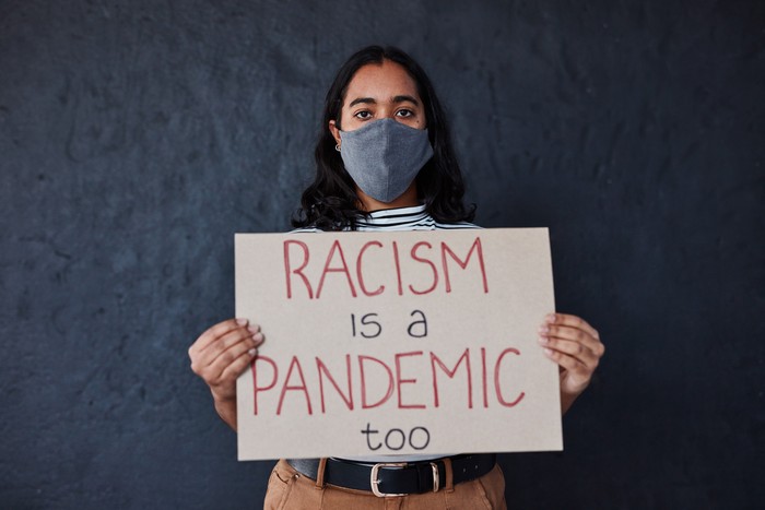 A man holding Racism is a Virus sign