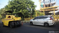 Tampak pula kendaraan melintas di samping proses pengaspalan jalan tersebut.