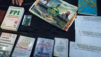Terdapat juga barang bukti senjata tajam seperti pedang dan buku Fisika Modern. Selain itu, dalam barang bukti yang dipajang ada juga poster bergambar Habib Rizieq Shihab (HRS). (Foto: Andhika Prasetia/detikcom)