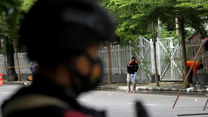 Anggota polisi berjalan dengan anjing pelacak saat mengumpulkan sisa serpihan ledakan bom bunuh diri di depan Gereja Katedral Makassar, Sulawesi Selatan, Senin (29/3/2021). Kepolisian masih melakukan olah TKP serta mengumpulkan serpihan sisa ledakan pada hari kedua pascaledakan bom bunuh diri yang terjadi pada Minggu (28/3/2021) di depan gereja tersebut. ANTARA FOTO/Arnas Padda/yu/aww.