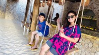 Nah, kalau yang satu ini adalah momen Thalita Latief saat liburan di pantai bersama anaknya. Mereka kompak naik ayunan sambil memegang segelas jus semangka. Foto: Instagram @thalitalatief