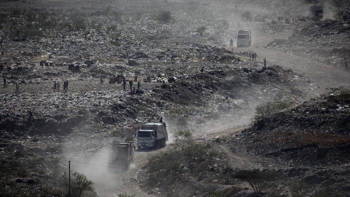 Duncan Wanjohi, right, and Kelvin Kimani, center, scavenge for recyclable materials on Sunday, March 28, 2021, from Dandora, the largest garbage dump in Kenya's capital of Nairobi. Their protective medical suits were found among material thrown away from hospitals. An estimated 20 million people around the world help keep cities clean by scavenging through landfills and dumps. Experts say these trash pickers, who sometimes toil alongside paid municipal sanitation workers, provide a vital service, yet they usually are not on a priority list for coronavirus vaccines.