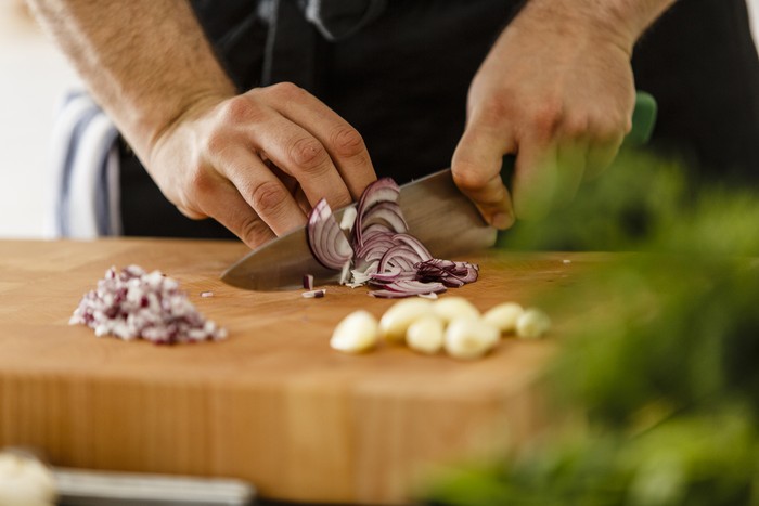 Slicing red onion on cutting board, close-up