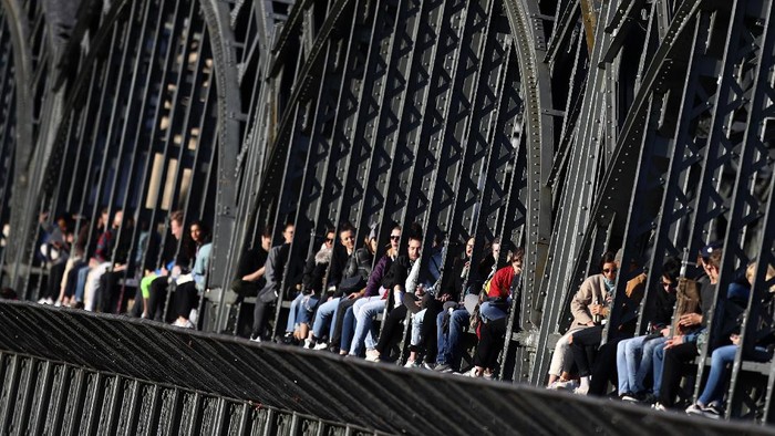 Young people enjoy the sunset at the bridge 'Hackerbruecke' in Munich, Germany, Sunday, March 28, 2021. (AP Photo/Matthias Schrader)