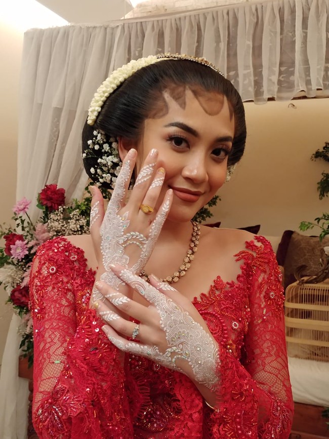 Canti Tachril menikah dengan Adipati Dolken pada Jumat (18/12/2020) di Bangka Belitung. Menurut pelukis henna @dewihenna, Canti Tachril meminta white henna dengan motif yang simple floral untuk malam midodaremi. Dalam foto ini, Chanti mengenakan kebaya pengantin warna merah, yang bertabur manik-manik. Foto: Dok.Instagram @dewihenna.