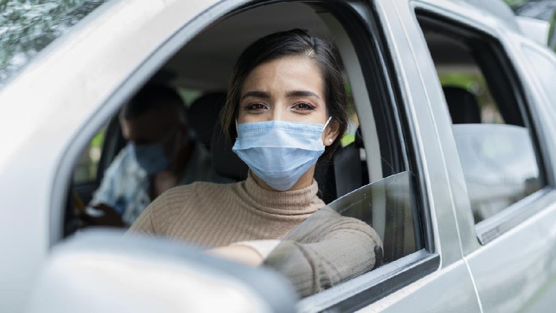 Ilustrasi mudik Beautiful Latin woman from Bogota Colombia between 20 and 29 years old, looks at the camera in a portrait and checks her cell phone waiting for a service to offer while wearing her mask