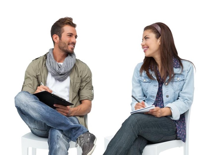 Full length of a cool young couple writing in notepads over white background