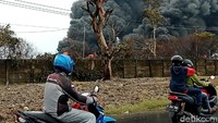 Warga tampak melintas di depan PT Pertamina (Persero) RU VI Balongan, Kabupaten Indramayu, yang masih terbakar.