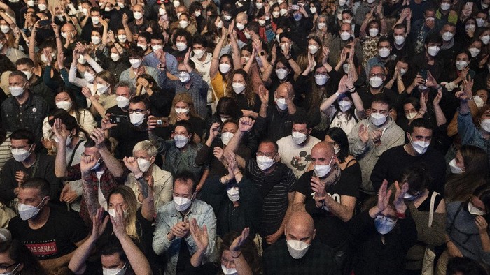 People take part in a music concert in Barcelona, Spain, Saturday, March 27, 2021. Five thousand music lovers are set to attend a rock concert in Barcelona on Saturday after passing a same-day COVID-19 screening to test its effectiveness in preventing outbreaks of the virus at large cultural events. The show by Spanish rock group Love of Lesbian has the special permission of Spanish health authorities. While the rest of the country is limited to gatherings of no more than four people in closed spaces, the concertgoers will be able to mix freely while wearing face masks. (AP Photo/Emilio Morenatti)