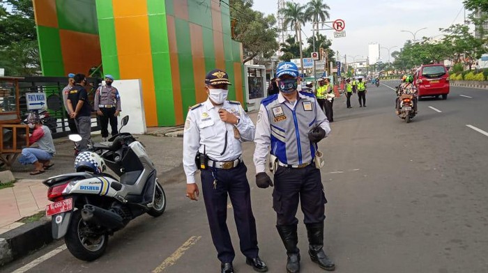 Petugas Dishun dan Polres Depok menggembok kendaraan yang parkir di dekat JPO Seberang Balai Kota Depok.