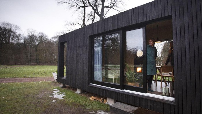 Cara Baru Berlibur di Masa Pandemi Kim Devos reads a book in a Slow Cabin in Elewijt, Belgium, Monday, Feb. 15, 2021. These Slow Cabins, set up the Belgian countryside, are the new way to vacation in pandemic times: in complete solitude and in the middle of nowhere. The wooden cabins are fully sustainable, provided you don't stay in the shower too long and you can live without Wi-Fi. (AP Photo/Virginia Mayo)