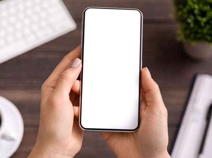 Woman demonstrating new modern smartphone with blank white screen for advertisement or application mockup