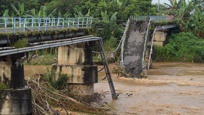Warga melihat kondisi jembatan yang putus di Sungai Madiun, Kota Madiun, Jawa Timur, Jumat (2/4/2021). Jembatan tersebut putus karena salah satu pilarnya ambruk akibat banjir yang terjadi Kamis (1/4) malam. ANTARA FOTO/Siswowidodo/rwa.