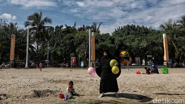 Sejumlah pengunjung menikmati Pantai Ancol, Jakarta Utara, Jumat (2/4).