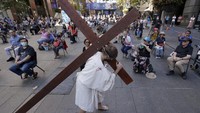 Timothy Watkins membawa salib selama perannya sebagai Yesus Kristus dalam pemeragaan Perjalanan ke Salib di Sydney, Australia, Jumat (2/4/2021) waktu setempat.  