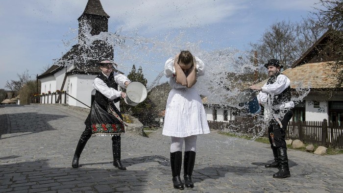 Tradisi Unik Rayakan Paskah di Desa Warisan UNESCO Dressed in folk costumes, young men pour water on young women in Holloko, a mountain village enlisted on the World Heritage List of Unesco, Hungary, Thursday, April 1, 2021, during a press event. Holloko is famous for its traditional Easter celebrations but this year all the events have been cancelled due to the coronavirus. (Peter Komka/MTI via AP)