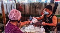 Seorang pedagang sedang melayani pembeli.