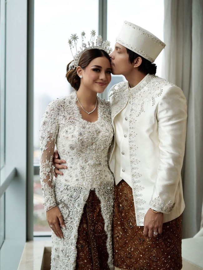 Aurel Hermansyah mengenakan busana adat Jawa modern saat akad nikah. Kebaya putih dengan hiasan kristal dan payet, serta aksen tulle pada bagian lengan karya Vera Anggraini membuat penampilannya makin anggun. Foto: Instagram @aurelie.hermansyah