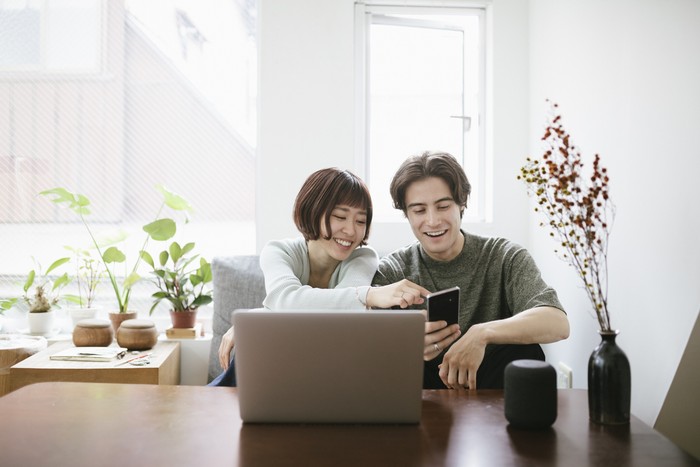 Couple sitting behind a coffee table, installing virtual assistant.