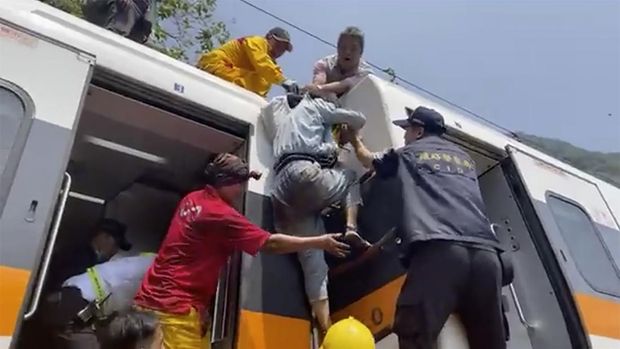 In this image made from a video released by hsnews.com.tw, a passenger, center, is helped to climb out of a derailed train in Hualien County in eastern Taiwan Friday, April 2, 2021. The train partially derailed along Taiwan’s east coast Friday, injuring an unknown number of passengers and causing potential fatalities. (hsnews.com.tw via AP)