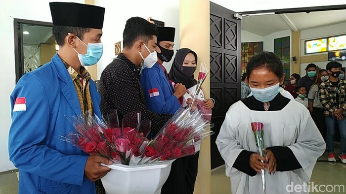 Sejumlah mahasiswa muslim membagikan bunga ke umat kristiani yang tengah merayakan Paskah